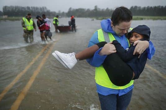 Worker carrying young girl out of floodwaters