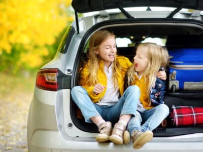 Little girls sitting in opened trunk of SUV