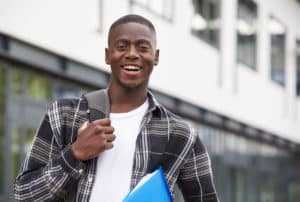 african american male college student wearing backpack and holding books