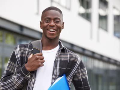 african american male student wearing backpack and holding books