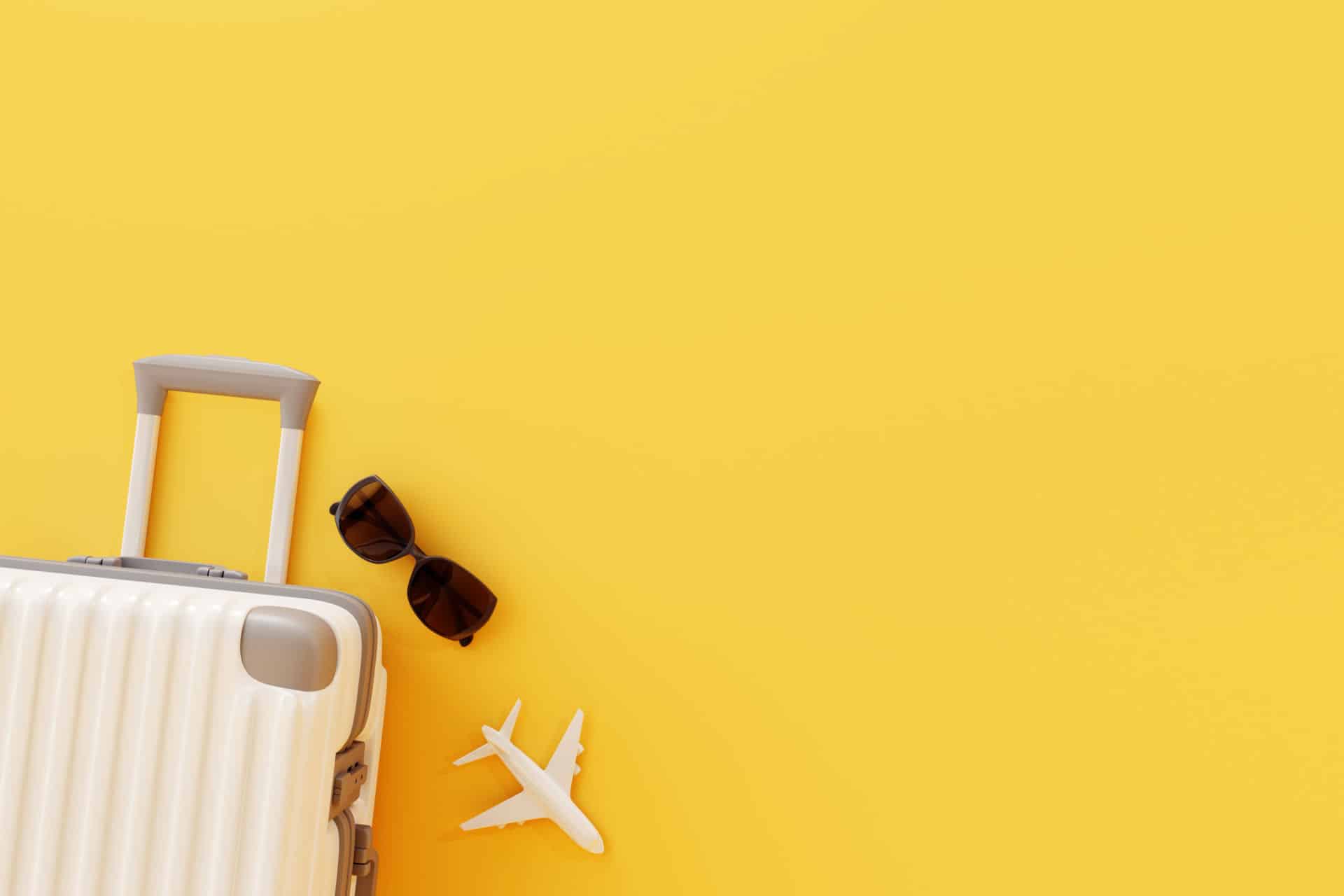 Flat lay white suitcase with sunglasses and plane on yellow background ...