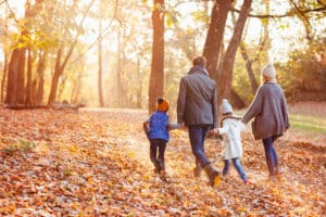Happy family walking on the beautiful autumn day in the leafy autumn scenery.