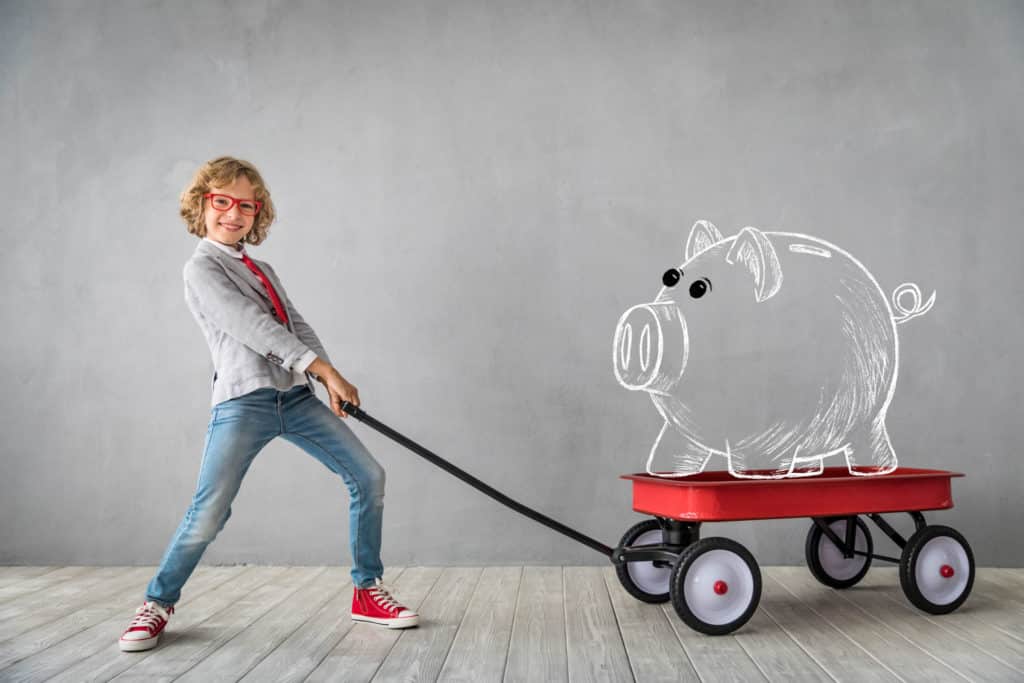 Young girl pulling wagon with outline of piggy bank