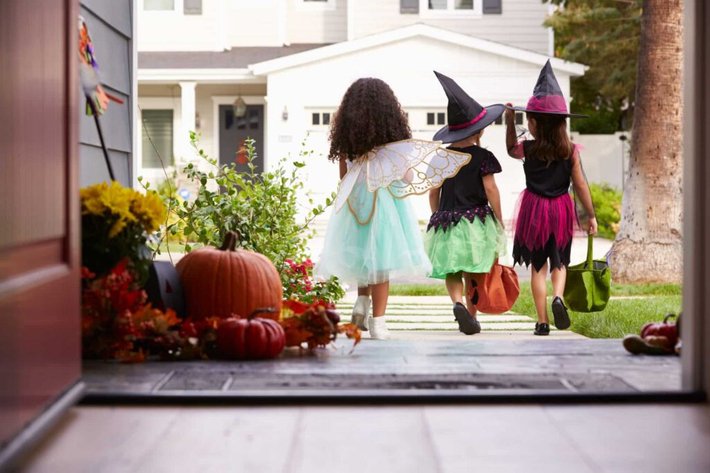 Girls in trick or treat costumes leaving house