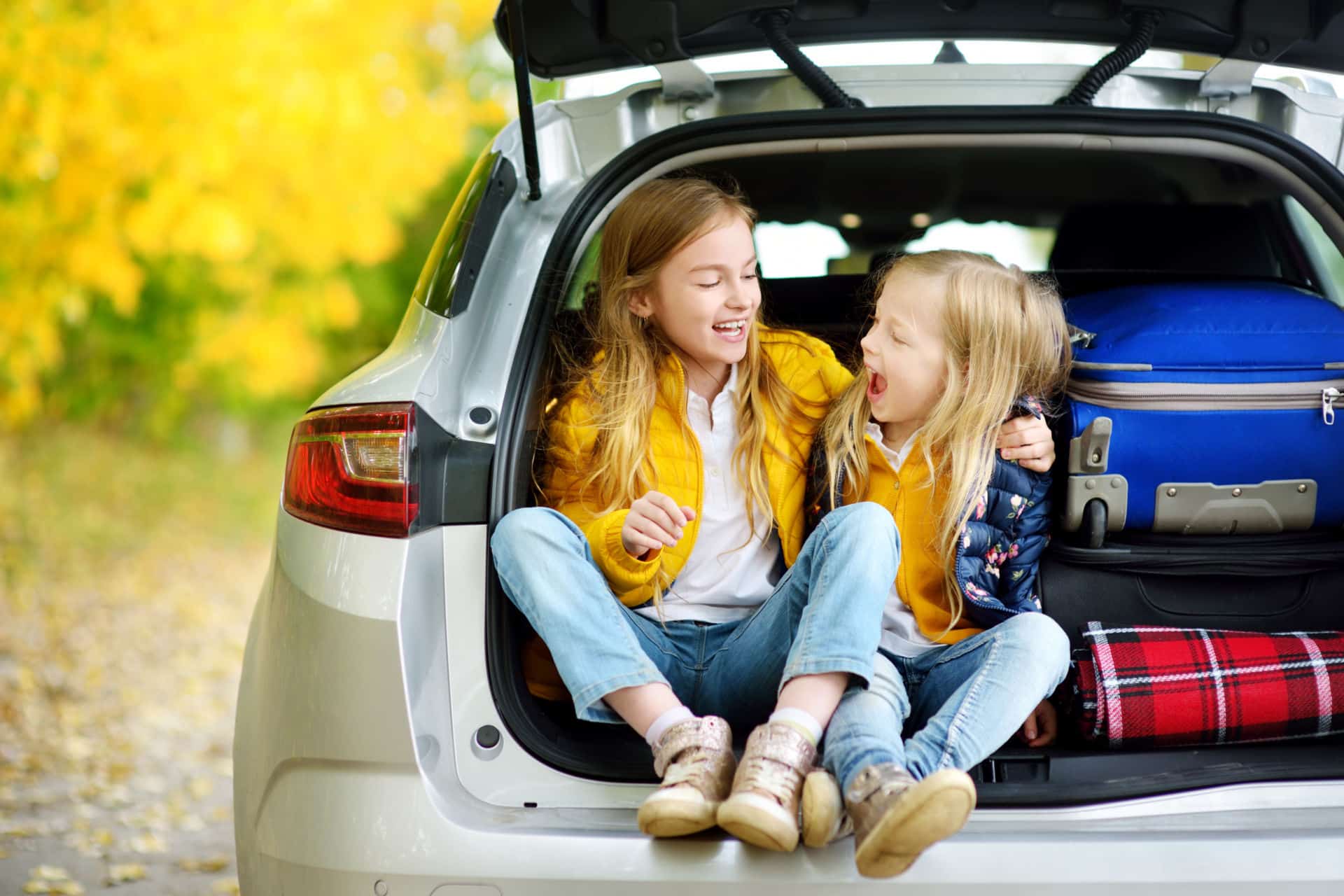 Little girls sitting in opened trunk of SUV